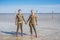 Two girls stand holding hands in the Baskunchak salt lake on a hot sunny day. Their bodies are smeared with healing mud