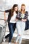 Two girls stand with suitcases at the airport and looking at the tablet. A trip with friends