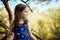 Two girls in summer dresses are climbing a tree in the forest