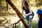 Two girls in summer dresses are climbing a tree in the forest