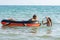 Two girls swim in the sea with an inflatable boat