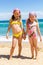 Two girls in swimwear on beach.