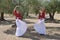 Two girls in a symmetrical position practicing flamenco with a skirt on the fly and looking up in an olive grove