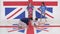 Two girls synchronically dance while two guys tape floor with british flag.