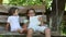 Two girls with tablet computer sit on the swing bench