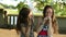 Two girls talking on cell phone standing in a Park.