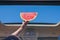 Two girls traveling by car and holding slice of watermelon in open hatch of a vehicle.