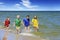 Two girls and two boys in colorful t-shirts running on a sandy beach