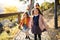 Two girls with unrecognizable parents in the background walking in park in autumn.