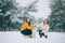 Two girls walk with a dog Alaskan Malamute in winter