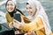 two girls wearing hijab laughing when looking video together with smartphone in the afternoon