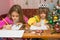 Two girls writing Christmas greeting letter sitting at the table at home