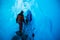 Two glacier guides walking into a large ice cave in Alaska