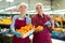 Two glad positive female employees hold a box of fresh ripe tangerines in their hands on citrus sorting line at