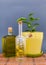 Two glass bottles olive oil stands near a flower against a dark background.