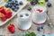 Two glass containers with plain yoghurt and berries on the table. Light summer mood