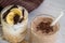 Two glass cups with ingredients banana, chocolate, oatmeal, yogurt and smoothie