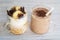 Two glass cups with ingredients banana, chocolate, oatmeal, yogurt and smoothie