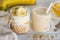 Two glass cups with ingredients banana, honey, oatmeal and yogurt and smoothie