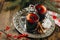 Two glass cups with mulled wine with citrus, apple and spices on silver tray with cinnamon sticks and cotton flower. Checked cloth