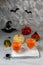 Two glass cups with pumpkin juice on a background of Halloween pumpkins on a gray wall with ghosts, bats, spiders, witch