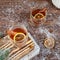 Two glass cups of tea with lemon, close-up of cinnamon sticks on a wooden table on a Christmas background. Warm healing