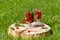 Two glass glasses with cherry , mint and water stand on a wooden stand with a crack on the green lawn on a Sunny day