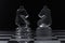 Two glass knight chess pieces facing each other