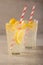 Two glass of lemonade with lemons and lime and straw, on a dark background, with space, a cool drink and summer mood