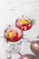 Two glass of pomegranate iced cocktail close up with rosemary and lemon on white marble background isolated with clear