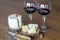 Two glass of red wine with few pieces of cheese at wooden background. side view.