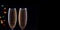 Two glasses with champagne with festive lights on a dark background