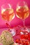 Two glasses with champagne tied with red ribbons on a pink background next to a souvenir heart and a candlestick heart with a