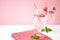 Two glasses with chilled drinks with raspberries stand on a white table against the background of a pink wall.