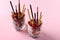 Two glasses with chocolate granola, banana and raspberry, decorated with sticks Pocky on pink background. When add Pocky, the