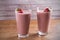 Two glasses of chocolate strawberry milkshake or cocktail on wooden table