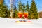 Two glasses of cold Aperol Spritz on tray of snow on sunny frosty day in winter, pines and fir trees on background. Restaurant or