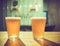 Two glasses of cold craft beer with white bubbles and shadow on wooden table at bar