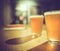 Two glasses of cold craft beer with white bubbles and shadow on wooden table at bar, vintage dark tone