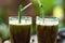 Two glasses of delicious avocado juice and a straw