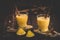 Two glasses of eggnogg with cinnamon sticks on dark wooden background