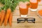 Two glasses of fresh carrot juice and black-rimmed spectacles