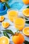 Two glasses of fresh juice  fruit squeezer and ripe fresh oranges on blue wooden table top  fresh orange juice making  top view
