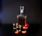 Two glasses and a glass bottle of plum liqueur with cut fruits on a black background