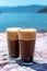 Two glasses with greek cold iced instant coffee with foam frappe on sunny beach