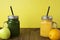 Two glasses with green and yellow detox smoothie with straws. Spinach and pumpkin smoothie on wooden table. Copy space