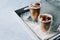 Two glasses of iced cappuccino coffee with ice on grey napkins on wooden tray. Copy space.