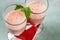 Two glasses with mixed fruit strawberry and raspberry in dense milk drink on red napkin.