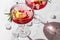 Two glasses of Pomegranate iced cocktail with rosemary and lemon on white marble background isolated with clear shadows