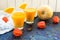 Two glasses of pumpkin juice and a pumpkin on a table decorated with physalis flowers. A concept of useful seasonal smoothies.